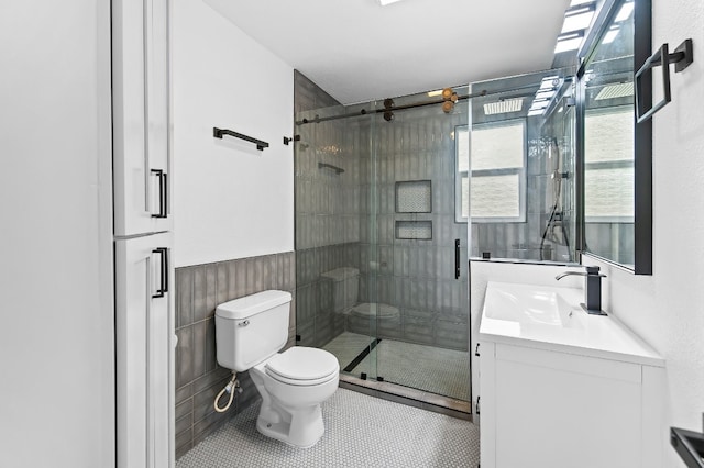 bathroom featuring tile walls, tile patterned flooring, a shower with shower door, vanity, and toilet