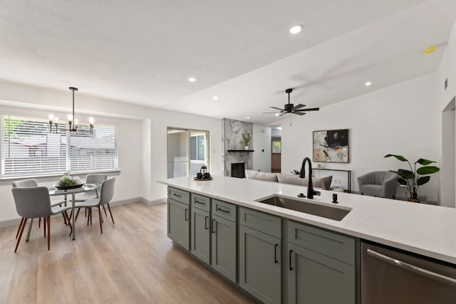 kitchen with light hardwood / wood-style floors, sink, a fireplace, decorative light fixtures, and stainless steel dishwasher