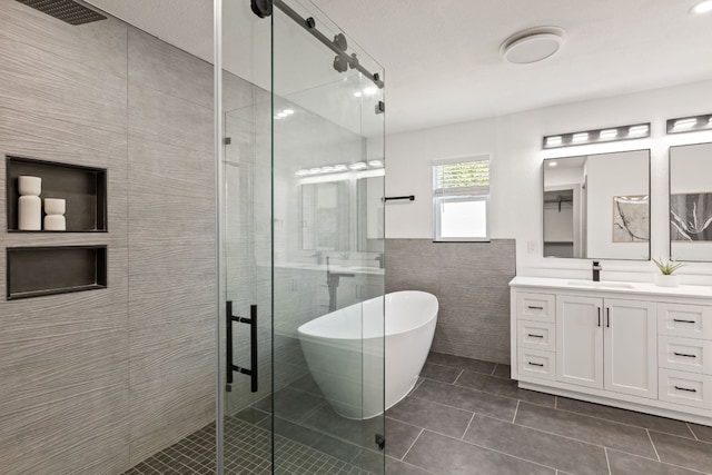 bathroom featuring tile walls, tile patterned flooring, vanity, and separate shower and tub