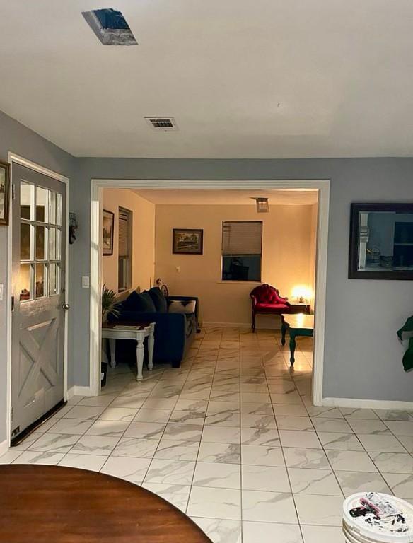 hall with marble finish floor, baseboards, and visible vents
