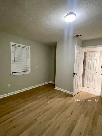 spare room featuring a textured ceiling and hardwood / wood-style flooring