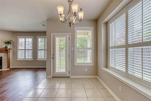 doorway featuring a tiled fireplace, light tile patterned floors, and a notable chandelier