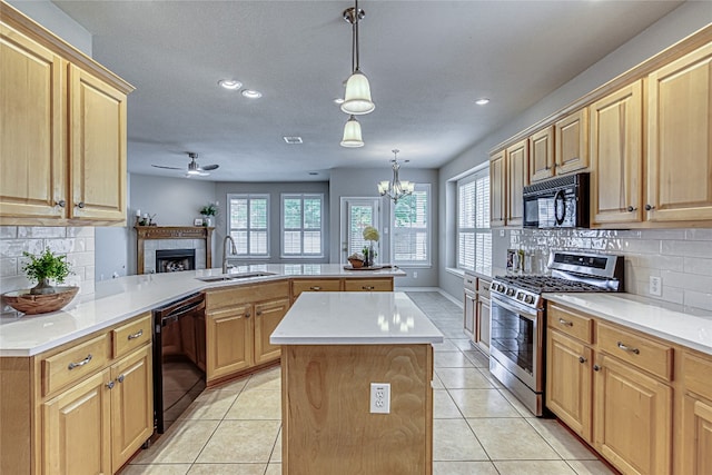 kitchen with decorative light fixtures, black appliances, sink, a center island, and kitchen peninsula