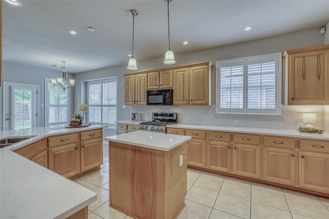 kitchen featuring hanging light fixtures, a center island, light brown cabinets, and stainless steel gas range