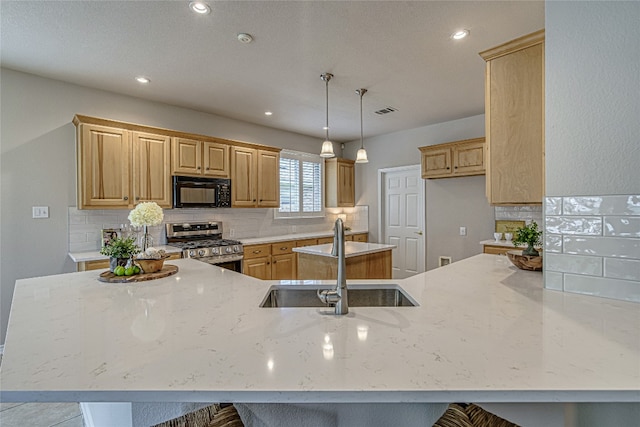 kitchen with pendant lighting, light stone counters, sink, and stainless steel gas range oven