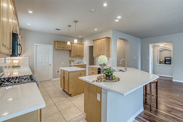 kitchen with sink, hanging light fixtures, a center island, light brown cabinetry, and decorative backsplash