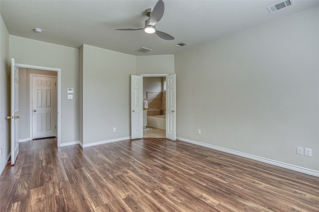 unfurnished bedroom featuring dark wood-type flooring, ensuite bath, and ceiling fan