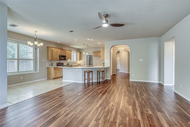 kitchen featuring hanging light fixtures, ceiling fan with notable chandelier, light hardwood / wood-style floors, and kitchen peninsula