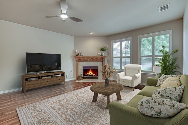 living room with a tiled fireplace, hardwood / wood-style flooring, and ceiling fan