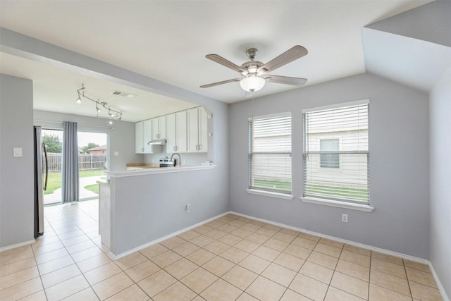 interior space with ceiling fan, vaulted ceiling, and light tile patterned flooring