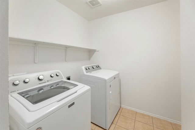 clothes washing area with washing machine and dryer and light tile patterned flooring