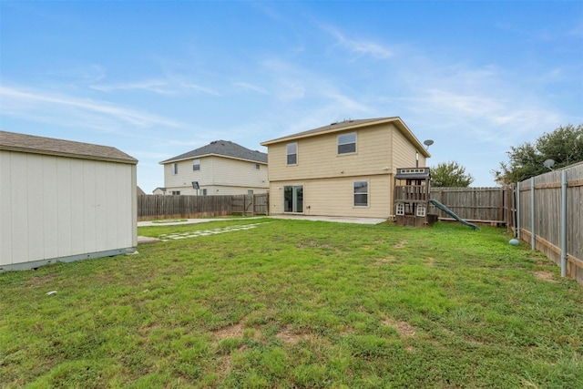 rear view of property featuring a storage unit, a lawn, and a playground