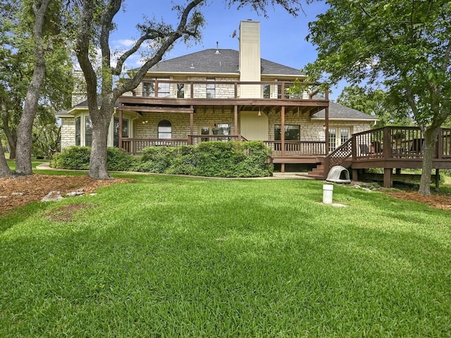 back of house featuring a lawn, roof with shingles, a deck, and a chimney