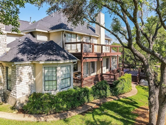 back of property featuring a wooden deck, a chimney, and a shingled roof