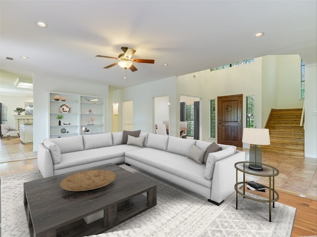 living room featuring ceiling fan, light wood-type flooring, and a fireplace