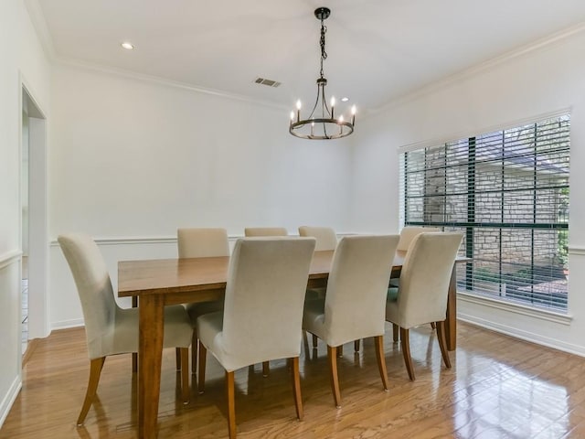 dining room with a notable chandelier, visible vents, crown molding, and light wood-type flooring