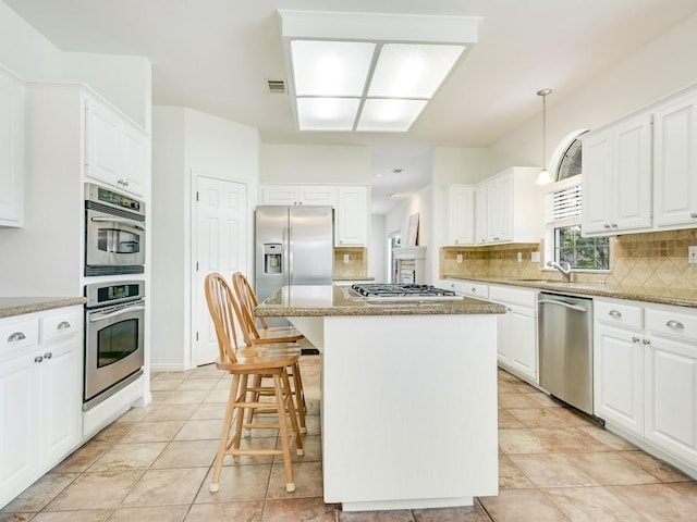 kitchen featuring a center island, backsplash, white cabinetry, and stainless steel appliances