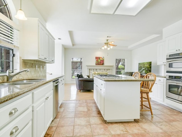 3503 Misty Creek Dr, Austin, TX 78735 - kitchen with a raised ceiling, appliances with stainless steel finishes, tasteful backsplash, ceiling fan, and a kitchen island