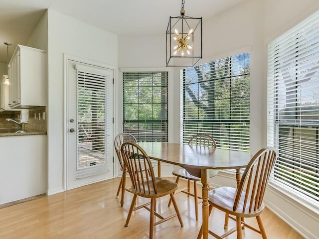 dining space with baseboards, a notable chandelier, and light wood finished floors