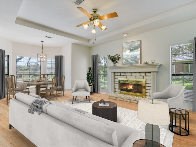 living room with plenty of natural light, ceiling fan with notable chandelier, light wood-type flooring, and a fireplace