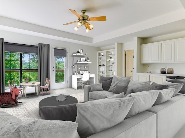 living room featuring light colored carpet, a raised ceiling, and a ceiling fan