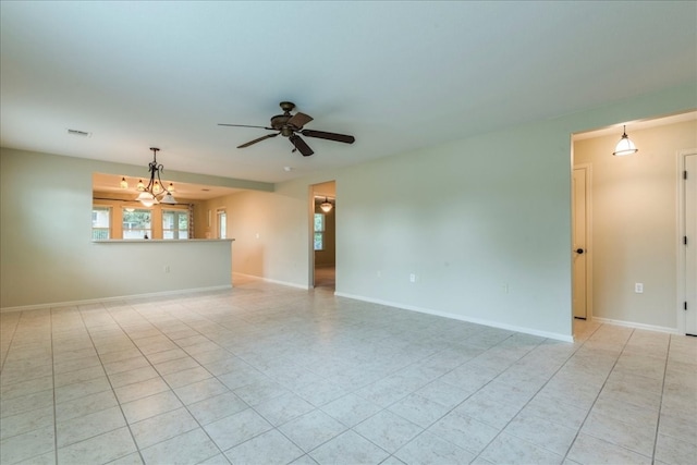 unfurnished room with ceiling fan with notable chandelier and light tile patterned floors