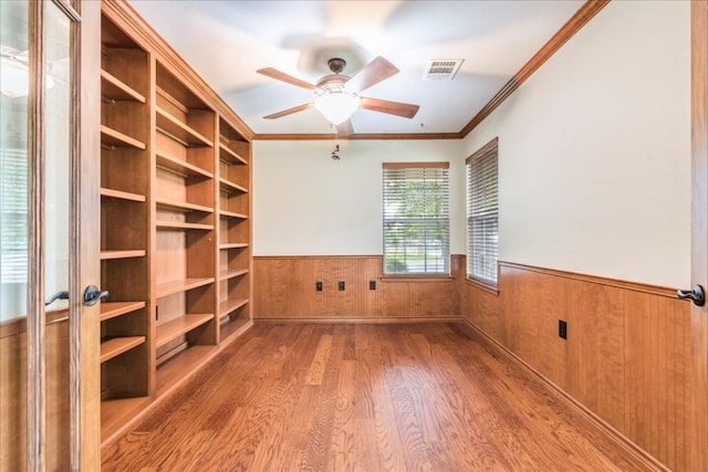 unfurnished office featuring ornamental molding, ceiling fan, wood walls, and hardwood / wood-style flooring