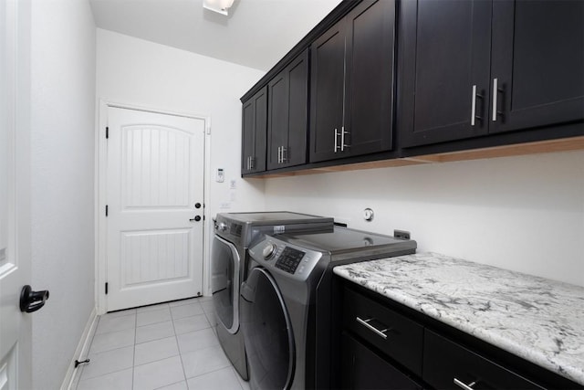 laundry room featuring washer and clothes dryer, light tile patterned floors, and cabinets