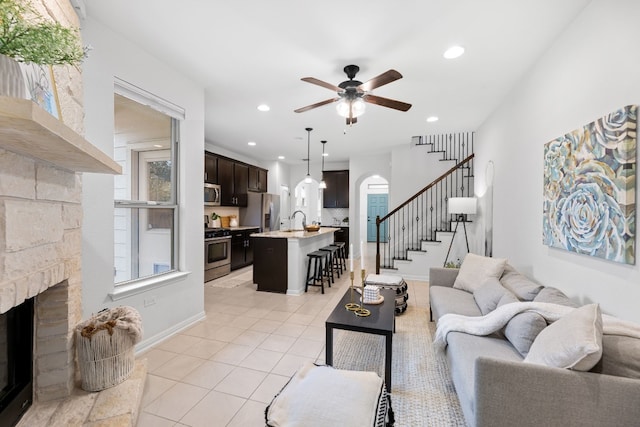 living room with ceiling fan, a fireplace, light tile patterned floors, and sink