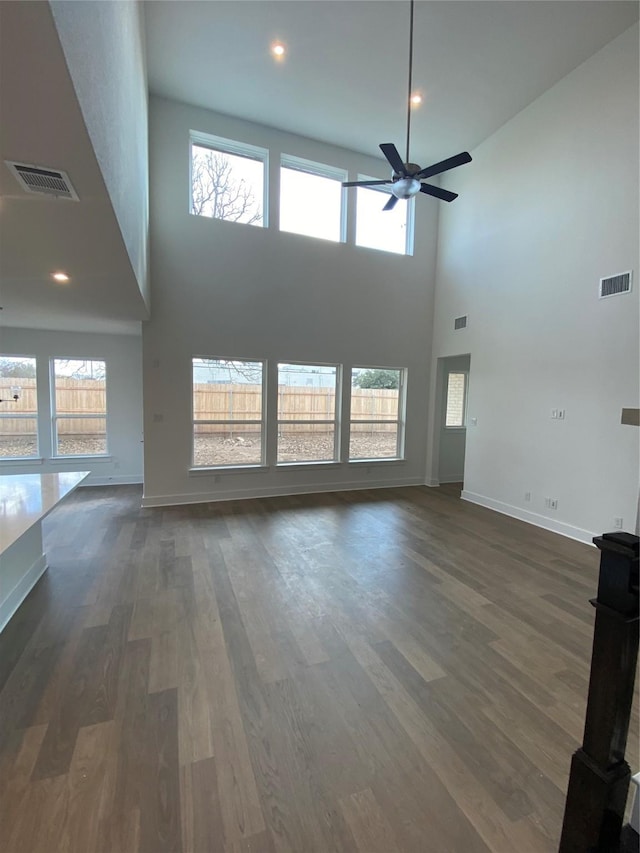 unfurnished living room featuring plenty of natural light, dark hardwood / wood-style floors, and a high ceiling