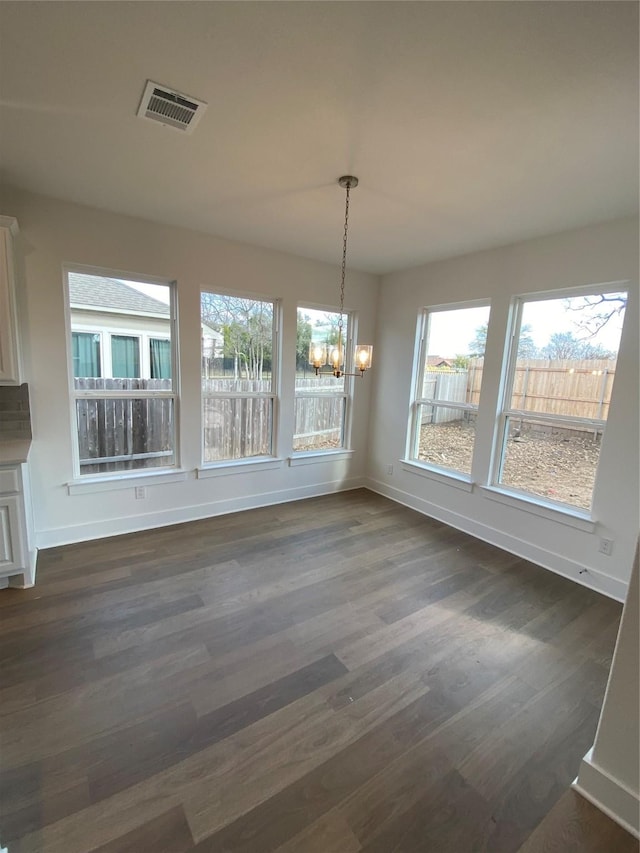 unfurnished dining area featuring a notable chandelier and dark hardwood / wood-style flooring