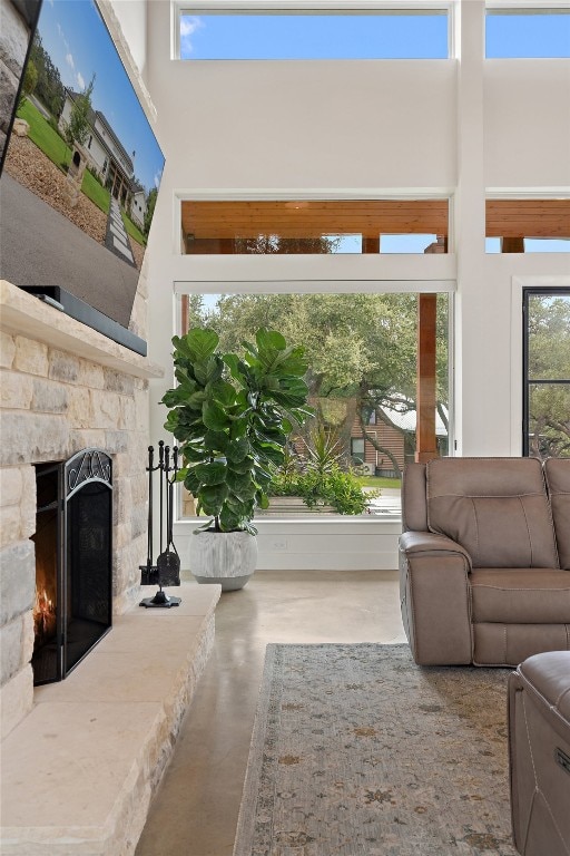 living room with concrete floors, a high ceiling, and a fireplace