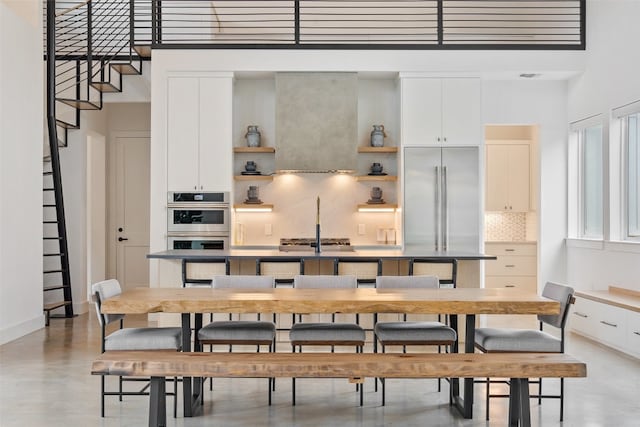 dining space featuring a high ceiling, concrete flooring, and sink