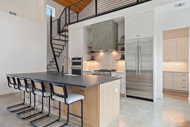 kitchen with a center island, stainless steel appliances, white cabinetry, and a high ceiling