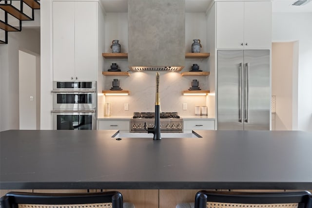 kitchen featuring a kitchen breakfast bar, stainless steel appliances, sink, decorative backsplash, and white cabinets