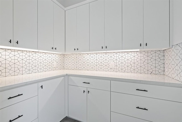 kitchen featuring backsplash, white cabinets, and light stone counters