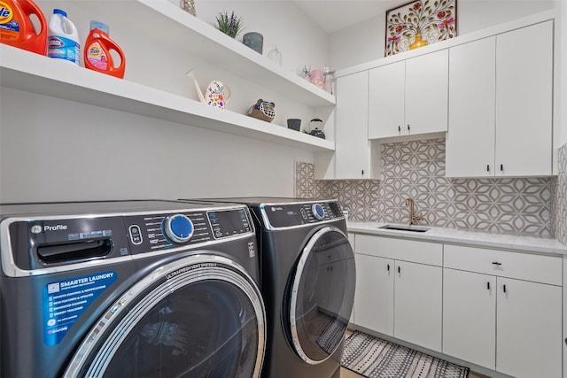 clothes washing area featuring cabinets, washer and clothes dryer, and sink