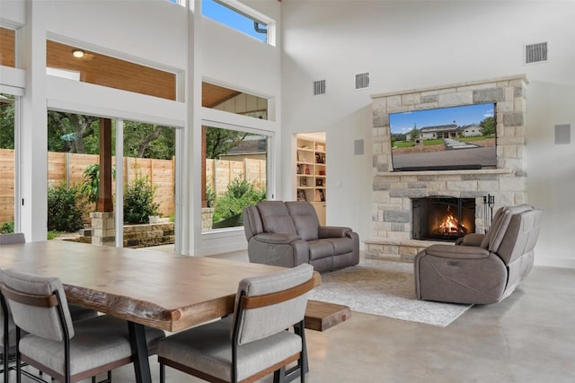 interior space featuring concrete flooring, a stone fireplace, and a towering ceiling