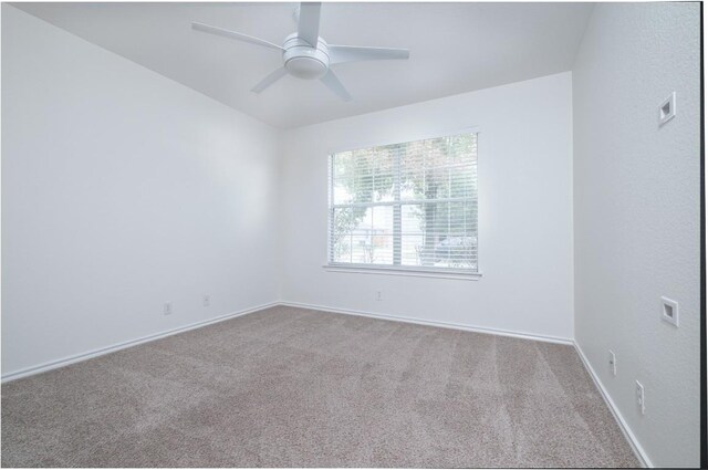 carpeted spare room featuring baseboards and a ceiling fan
