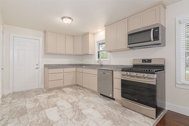 kitchen featuring cream cabinets, light stone countertops, and appliances with stainless steel finishes