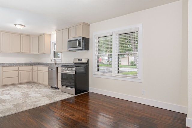 kitchen with appliances with stainless steel finishes, wood-type flooring, sink, and cream cabinets