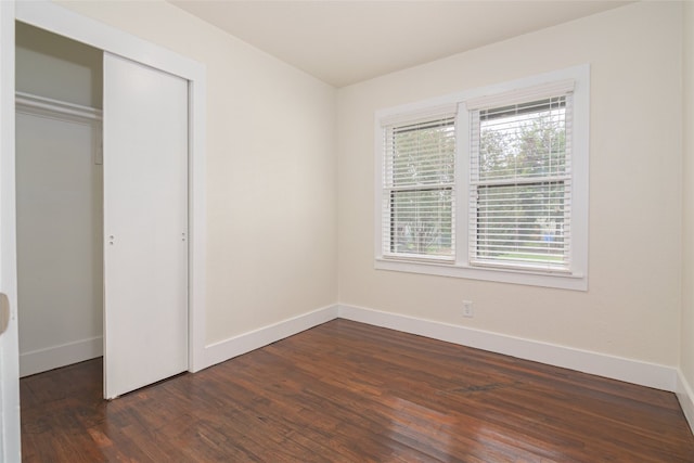 unfurnished bedroom with dark wood-type flooring and a closet