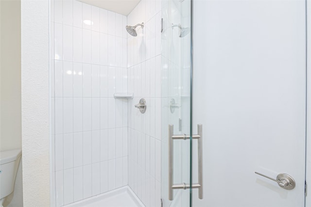 bathroom featuring a shower with door and toilet