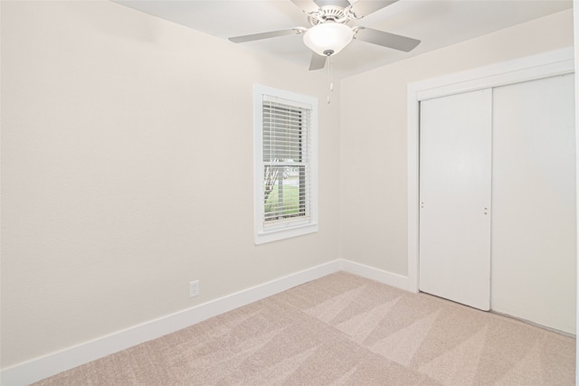 unfurnished bedroom featuring light colored carpet, ceiling fan, and a closet