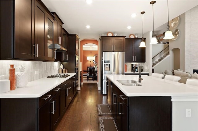 kitchen featuring dark brown cabinets, an island with sink, sink, dark wood-type flooring, and appliances with stainless steel finishes