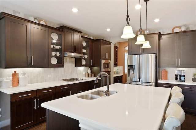 kitchen with an island with sink, stainless steel appliances, sink, and dark brown cabinets