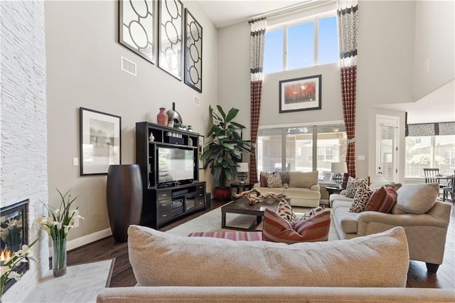 living room featuring a fireplace, dark hardwood / wood-style flooring, and a high ceiling