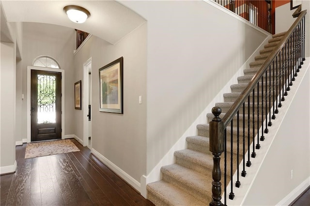 foyer entrance with dark hardwood / wood-style flooring and a towering ceiling