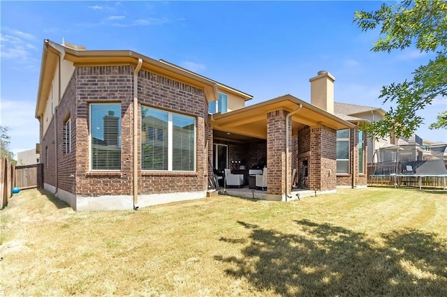 back of property featuring a trampoline, a yard, and a patio