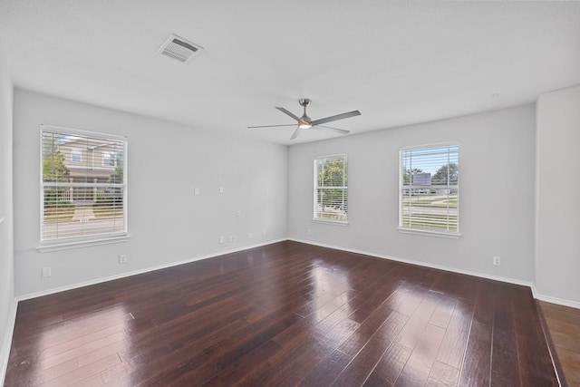 empty room featuring dark hardwood / wood-style flooring, a healthy amount of sunlight, and ceiling fan